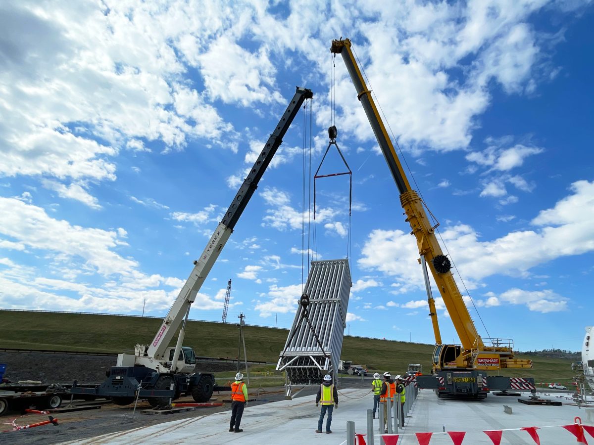 Two cranes position one of eight 34.5-foot-tall vaporizers into place at the new Wolf Creek Dam cryogenic facility in Jamestown, Kentucky on March 26, 2025. This system will allow the U.S. Army Corps of Engineers to diffuse oxygen into the upstream Cumberland reservoir, boosting hydropower efficiency. (Courtesy photo)